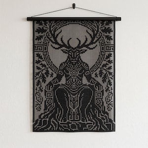 Puede incluir: Un tapiz de pared en blanco y negro con una ilustración geométrica pixelada de una figura sentada con grandes astas. El diseño está enmarcado por hojas estilizadas y patrones intrincados, suspendido de una varilla negra horizontal.