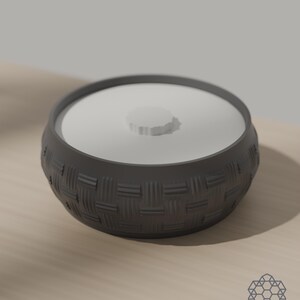 Dark grey woven storage bowl with white drop-in lid on a sunlit table. 3D-rendered visualization of the exact print file.