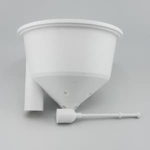 The white soil insert seen from the side, showing its cone shaped underside and the tube that runs down into the reservoir, with the separate white float stick lying in front of it.