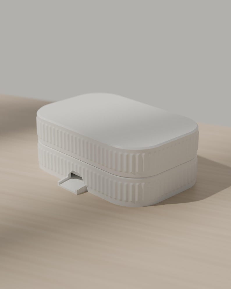 May include: A matte white rectangular storage box with rounded corners and a ribbed, vertical texture along the sides. The container features a two-part design with a lid and a small, protruding tab on the front edge for opening the lid.