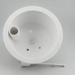 Angled view down into the white insert, with the raised fill tube opening set into the inner wall, small drainage holes across the floor, and the white float stick resting behind it.