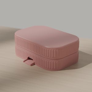 May include: A dusty rose rectangular storage box with rounded corners and a ribbed, textured exterior. The container features a hinged lid design with a small, protruding tab on the front edge for opening, showcasing a clean and simple aesthetic.