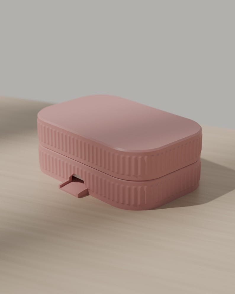 May include: A dusty rose rectangular storage box with rounded corners and a ribbed, textured exterior. The container features a hinged lid design with a small, protruding tab on the front edge for opening, showcasing a clean and simple aesthetic.