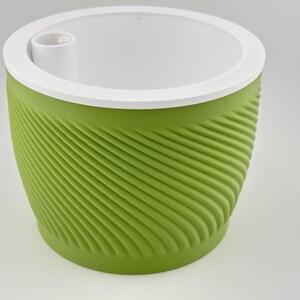 The green spiral planter seen from a higher angle with the white insert in place, showing the raised fill tube opening set into the white top where water is poured in.