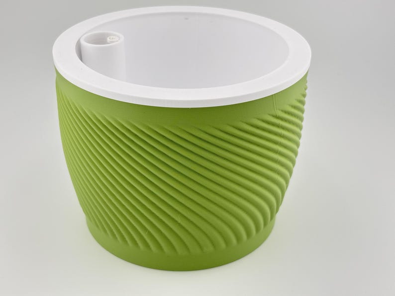 The green spiral planter seen from a higher angle with the white insert in place, showing the raised fill tube opening set into the white top where water is poured in.
