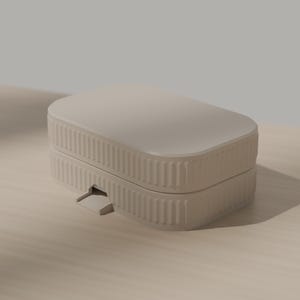 May include: A rectangular, light beige storage box with rounded corners and a ribbed, vertical texture along the sides. The container features a flat lid and a small, protruding latch mechanism on the front edge, constructed from a solid material.