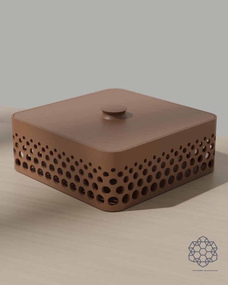 May include: A square, matte brown storage box with a flat lid and a small central knob. The sides feature a perforated pattern of circular cutouts that vary in size, creating a gradient effect. A small geometric logo is visible in the corner.