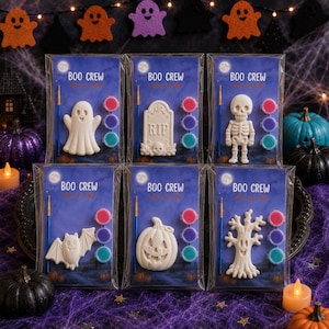 Puede incluir: Seis kits de pintura Boo Crew individuales en envases de plástico transparente. Cada kit contiene una figura de cerámica blanca, un pincel azul y tres botes de pintura pequeños. Las figuras incluyen un fantasma, una lápida, un esqueleto, un murciélago, una calabaza y un árbol.