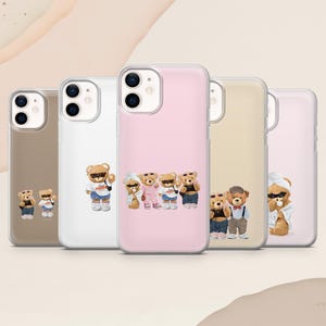 May include: Five clear smartphone cases arranged in a row, each featuring different illustrations of teddy bears wearing various outfits, sunglasses, and accessories. The cases have dual camera cutouts and are displayed against a neutral background.