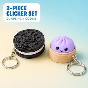 May include: A 2-piece clicker set featuring a black and white sandwich biscuit keychain and a purple dumpling in a tan steamer basket keychain. The text 2-PIECE CLICKER SET DUMPLING + COOKIE is displayed above the two items on a gradient background.