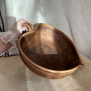 Può includere: Una ciotola in ceramica a forma di foglia con una finitura marmorizzata marrone. La ciotola presenta un manico curvo su un lato e un piccolo beccuccio sul lato opposto. Le superfici interne ed esterne mostrano un motivo vorticoso di toni.