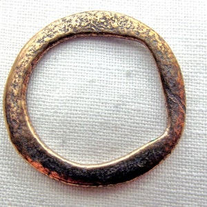 May include: A simple, circular, bronze ring with a rough, textured surface.