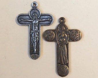 Może przedstawiać: Dwa srebrne metalowe krzyże z religijnymi obrazami. Jeden krzyż przedstawia wizerunek Jezusa Chrystusa na krzyżu, a drugi krzyż przedstawia wizerunek Matki Boskiej trzymającej Dzieciątko Jezus.