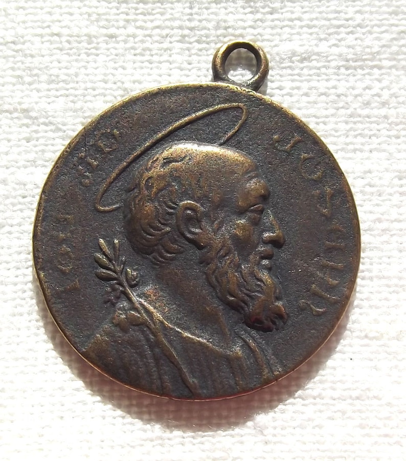 May include: A bronze medal with a profile of a man with a beard and halo. The medal has the inscription "S. IOHANNES BAPTISTA" around the edge.