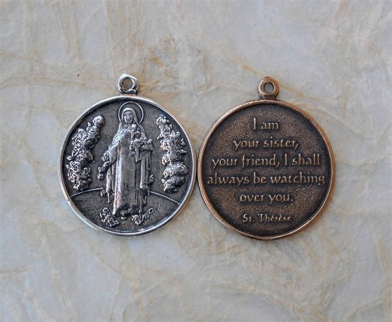 Op de afbeelding: Een zilveren en bronzen medaille met een afbeelding van Sint Theresia van Lisieux aan de ene kant en een citaat van haar aan de andere kant. Het citaat luidt: "Ik ben je zus, je vriendin, ik zal altijd over je waken. Heilige Theresia."
