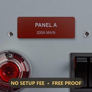 May include: A rectangular dark red identification label with white text reading PANEL A and 200A MAIN, mounted on a light gray surface between two silver screws, positioned above a circular red indicator light and a black dual rocker switch.