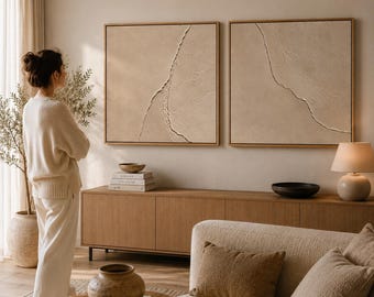 May include: Two square beige textured wall art pieces in light wood frames hanging side by side. Each canvas features a prominent, jagged, raised diagonal line running across the surface, creating a relief effect with subtle shadows and depth.