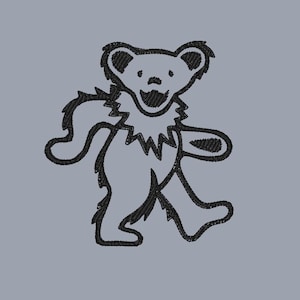 Puede incluir: Un parche bordado negro que presenta el contorno de un oso bailarín con un cuello de volantes. El diseño está realizado con hilo negro grueso sobre un fondo gris claro sólido, mostrando la icónica figura del oso en una pose de caminar.