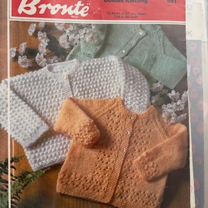 May include: A Bronte Double Knitting pattern booklet 491 featuring three long-sleeve cardigans in white, peach, and light green. The cover displays the text 'Bronte', 'Double Knitting', '491', and 'To fit 41 to 51 cm chest (16 to 20 inch)'.