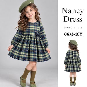May include: A Nancy Dress sewing pattern for sizes 06M-10Y. The dress features a long-sleeved, knee-length design in a navy blue, dark green, and yellow plaid fabric with a small black bow at the waist and a matching olive green beret.
