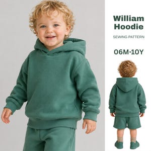 Op de afbeelding: Een William Hoodie naaipatroon voor maten 06M-10Y. De afbeelding toont een effen donkergroene hoodie met lange mouwen en een bijpassende korte broek, weergegeven in voor- en achteraanzicht op een kindermodel.