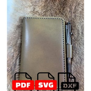 May include: A rectangular olive green leather notebook cover with visible edge stitching and a matching leather pen loop holding a dark metal pen. The image includes three file format icons labeled PDF, SVG, and DXF at the bottom.