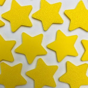 Peut inclure: Une collection de plusieurs formes d'étoiles à cinq branches d'une couleur jaune vif. Chaque étoile présente une surface texturée et est disposée selon un motif dispersé sur le cadre, affichant des pointes géométriques uniformes.
