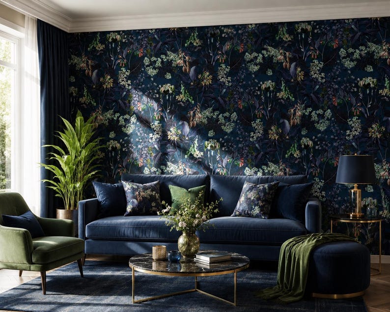May include: A dark blue velvet sofa with matching throw pillows, a green armchair, a round marble coffee table, and a dark blue ottoman. The wall features dark floral wallpaper with blue, green, and white botanical patterns and foliage.