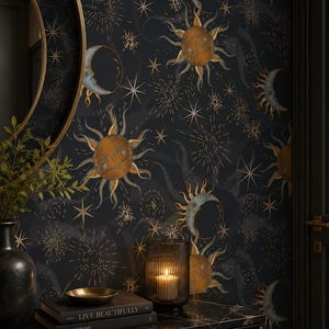 May include: Wallpaper featuring a dark black background with a repeating pattern of golden suns and blue crescent moons, interspersed with various star shapes and radiating light bursts. The design includes celestial motifs in a vintage style.