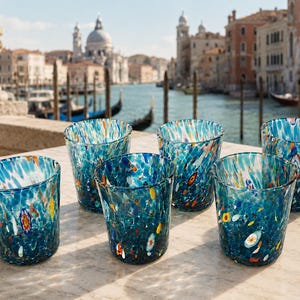 Peut inclure: Un ensemble de cinq verres à boire présentant une couleur de base bleu vif avec des motifs tachetés en blanc, orange et jaune. Chaque verre a une forme cylindrique avec un bord légèrement plus large, affichant un design multicolore.