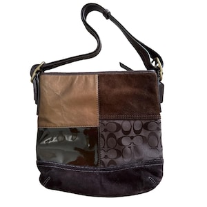 Puede incluir: Un bolso de hombro con múltiples texturas que presenta un diseño de patchwork de cuero marrón, ante marrón oscuro, cuero charol marrón oscuro brillante y un panel de tela marrón oscuro con un patrón de logotipo repetido y correa ajustable.