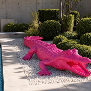 Può includere: Una grande scultura di alligatore rosa brillante con una superficie ruvida e squamosa e la bocca aperta, posizionata su un letto di ghiaia bianca accanto a una piscina. La scultura presenta creste dettagliate lungo la schiena e la coda.