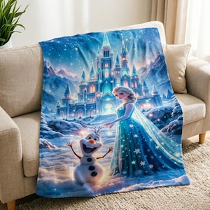 以下が含まれることがあります： 長い青いドレスを着た金髪のキャラクターと、笑顔の雪だるまが描かれた鮮やかでカラフルなプリントの柔らかいブランケット。背景には、雪に覆われた山々の冬の風景の中に、大きく輝く氷の城が描かれています。
