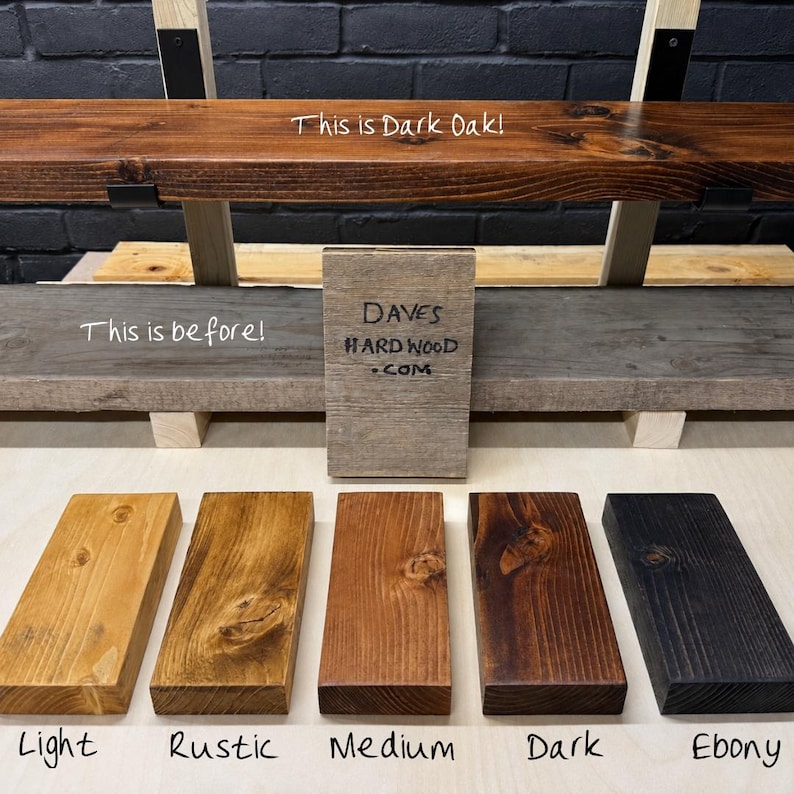 Puede incluir: Una muestra de cinco tablas de madera rectangulares con diferentes tonos de tinte etiquetadas como Light, Rustic, Medium, Dark y Ebony. Un letrero central dice DAVES HARDWOOD.COM, con el texto adicional This is Dark Oak! y This is before!