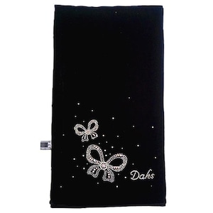May include: A rectangular black velvet scarf featuring two bow-shaped embellishments made of small clear crystals. The design includes scattered crystal accents and the word Daks written in a cursive script using the same clear crystal material.