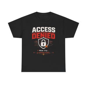 Pode incluir: Uma t-shirt preta de manga curta com um gráfico que apresenta o texto branco ACCESS e o texto vermelho DENIED sobre um ícone de escudo com um cadeado e um pequeno triângulo de aviso laranja. Abaixo está o texto > Nice try._ C-CONNECTIONS™.