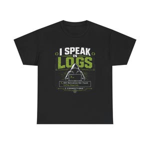 May include: A black short-sleeve t-shirt featuring a graphic of a hooded figure at a laptop. The text reads I SPEAK IN LOGS, 404 Motivation Not Found, Coffee Required, and C-CONNECTIONS. The design uses white and green accents on the black fabric.
