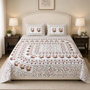 May include: A white bedspread and two matching pillowcases featuring a repeating pattern of stylized peacocks in shades of brown, orange, and blue, accented by a floral border and a delicate vine motif across the lower section of the fabric.
