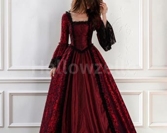 May include: A floor-length gown in deep red with a square neckline and long, flared sleeves. The dress features black lace trim along the bodice, sleeves, and skirt panels, with a textured damask pattern on the sides and a solid red center panel.