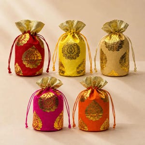 May include: Five cylindrical drawstring pouches in red, yellow, beige, pink, and orange. Each pouch features a metallic gold floral pattern and a gold fabric top section with matching drawstring cords for closure, arranged in two rows.