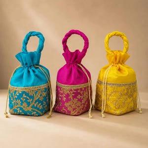 May include: Three drawstring pouches in bright turquoise, magenta, and yellow. Each bag features a braided handle, a gathered top, and a lower section decorated with intricate gold floral embroidery and a matching gold trim border.