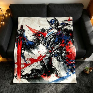 May include: A rectangular throw blanket featuring a dynamic, artistic illustration of a robotic character in shades of blue, white, and black, accented by bold, abstract splashes of bright red paint and a prominent red sword held by the figure.