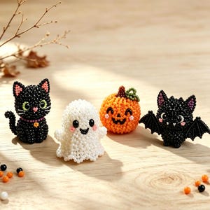 May include: A set of four small beaded figurines featuring a black cat with a purple collar, a white ghost, an orange pumpkin with a green stem, and a black bat with pink inner ears. Each figure is crafted from tiny beads with detailed facial features.