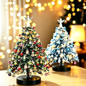 Peut inclure: Deux sapins de Noël artificiels miniatures sur des bases circulaires noires. Le sapin au premier plan est vert avec des ornements multicolores et un ange au sommet. Le sapin à l'arrière est bleu et blanc avec des ornements bleu clair et un ange.