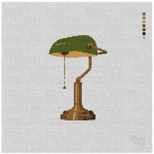 May include: A cross-stitch pattern of a banker lamp featuring a green shade, a brass-colored base, and a pull chain. The design is set against a white grid background with a color palette key displayed in the upper right corner of the image.