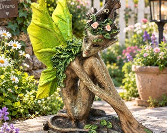 Puede incluir: Una escultura de jardín de una figura sentada con grandes alas de color verde brillante en forma de hoja. La figura tiene un cuerpo marrón texturizado similar a la madera, una corona de pequeñas flores rosas y hojas verdes sobre la cabeza.
