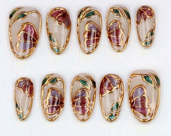 Unghie finte a farfalla di lusso, elegante nail art in smalto dorato, ali rosse viola e fogliame verde con vetrate colorate, unghie floreali