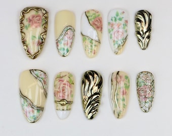 Uñas postizas de lujo hechas a mano, estilo vintage barroco, con estampado floral y detalles dorados, forma almendrada. Diseño de uñas retro y glamuroso.