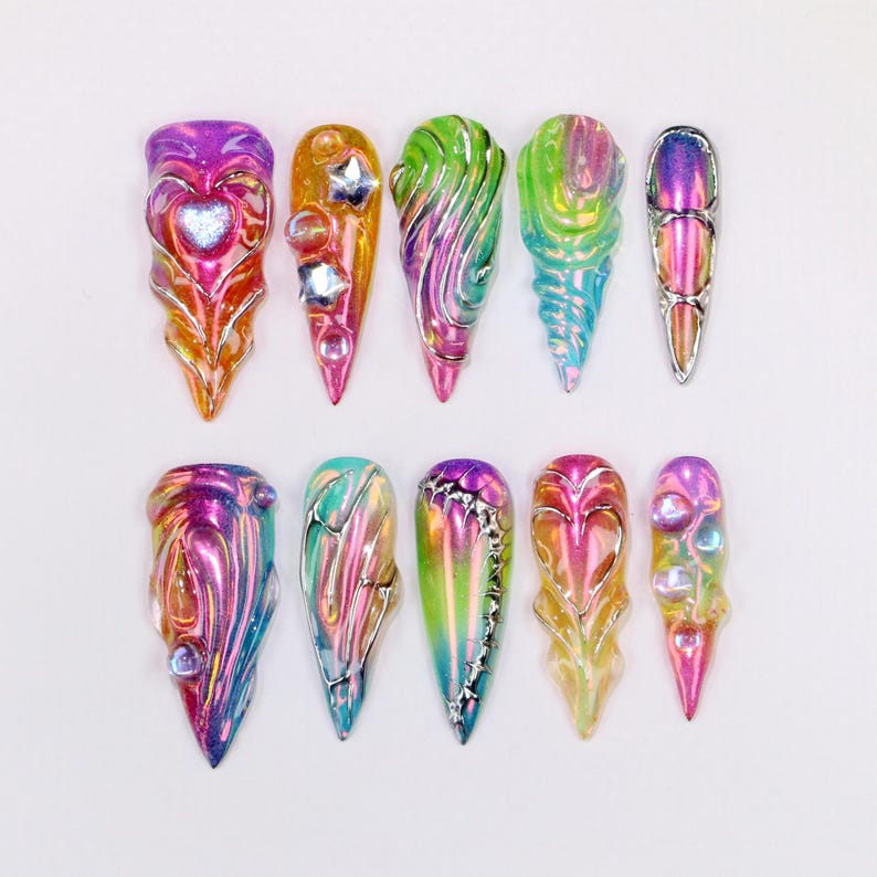 May include: A collection of ten iridescent, sculpted nail art designs. Each nail features a unique shape and color palette, including pink, orange, green, and blue. Some nails have embedded embellishments like stars and hearts.