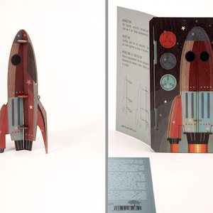 May include: A flat-pack wooden rocket ship model kit featuring a dark brown, red, and light blue color scheme with star accents. The set includes a pre-cut board with rocket components and a fully assembled three-dimensional rocket structure.